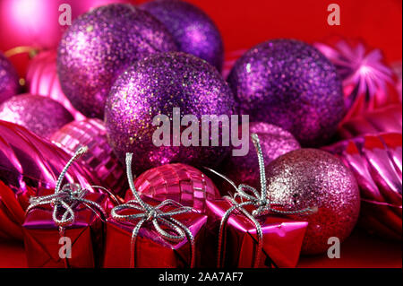 Cadeaux en boîte avec de l'argent liée string s'asseoir en face de violet et rose boules de Noël Banque D'Images