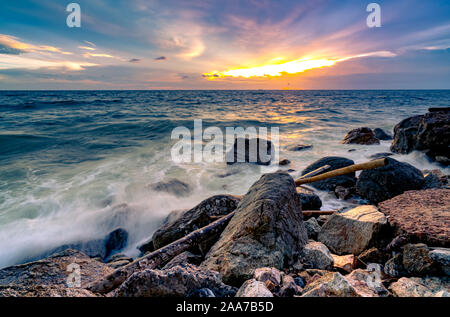 L'eau de l'océan des vagues sur la plage de rock avec beau coucher de soleil Ciel et nuages. Éclaboussures des vagues de la mer sur la pierre en mer sur la côte de l'été. Nature Paysage. Scieries Banque D'Images