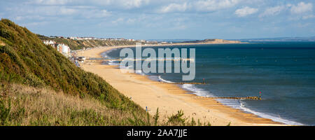 Les gens marchent le long de la plage de Boscombe Bournemouth, avec Hengistbury Head derrière. Banque D'Images