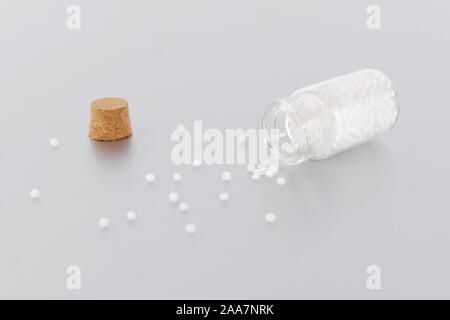 Globules homéopathiques dans une bouteille en verre sur gris Banque D'Images