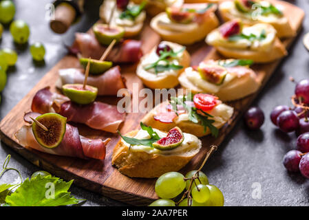 Assortiment de brushetta - italien apetizer ou des tapas espagnoles traditionnelles pour le partage. Cuisine de fête sur le plateau de restauration. Antipasti avec de la viande, du fromage et des fruits Banque D'Images