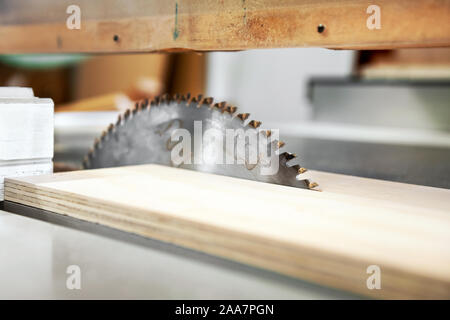 Close up low angle view d'une lame de scie circulaire à dents avec planche de bois dans un atelier de travail du bois ou menuiserie Banque D'Images