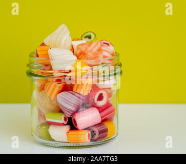 Candy coloré dans le pot de verre contre le mur couleur olive sur le tableau blanc Banque D'Images