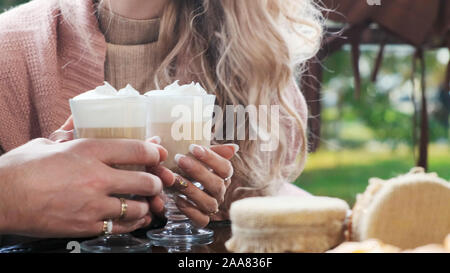 Couple dans un café sur la terrasse. Close-up mains des amoureux l'homme et la femme tenir les tasses avec du cappuccino et latte Banque D'Images