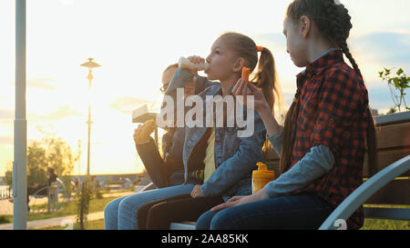 Trois écolières amis sont assis sur un banc et de manger. Pause déjeuner à l'école Banque D'Images