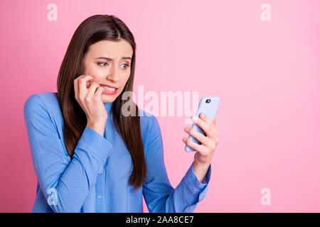 Tourné photo de déçu fâché triste voir des résultats d'examens des étudiants sur son téléphone avec mains ongles mordant face portant l'expression malheureuse Banque D'Images