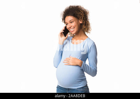 Happy black pregnant woman talking on smartphone Banque D'Images