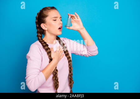 Photo du profil de jolie dame avec de longues tresses, souffrant d'asthme inhalateur de bouteilles pour arrêter la toux porter casual pull rose bleu isolé Banque D'Images