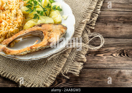 Le poisson frit avec salade et pommes de terre, dîner traditionnel sur plaque, concept de cuisine Banque D'Images