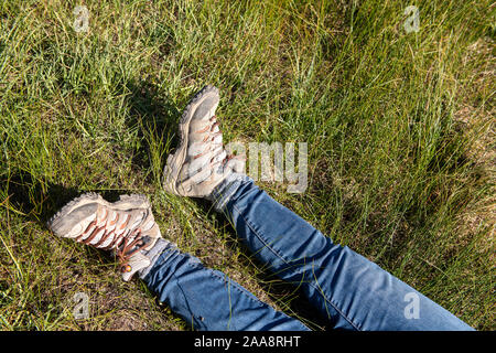 Jambes en jeans et des bottes de randonnée portant dans les hautes herbe verte Banque D'Images