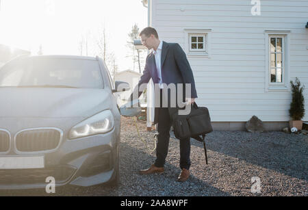 Son débourrage homme voiture électrique de quitter la maison pour aller travailler Banque D'Images