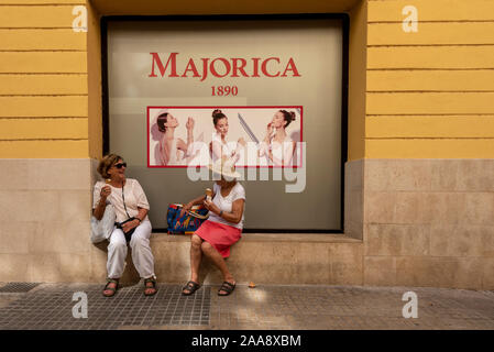 Palma, Espagne. 10 Oct, 2019. Deux dames âgées assis devant une affiche publicitaire du producteur Majorica bijoux et manger une glace dans le centre de Palma de Majorque. Credit : Stephan Schulz/dpa-Zentralbild/ZB/dpa/Alamy Live News Banque D'Images