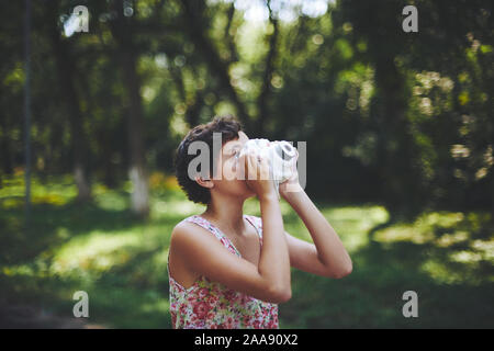 Preteen girl enthousiaste sensibilisation et de prendre l'appareil photo instantané photo dans Green Park Banque D'Images