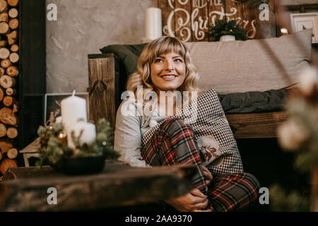 Belle jeune femme en pyjama près de cheminée décorative. Ambiance de Noël, Nouvel an Banque D'Images