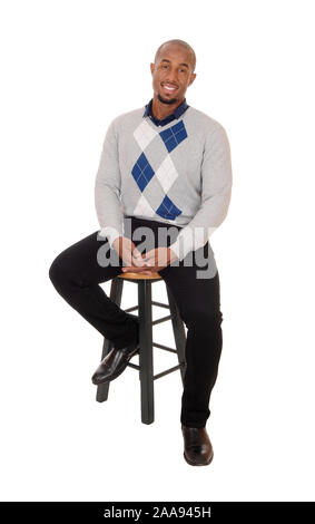 Un beau jeune homme afro-américain assis dans le studio de tout le corps, de la pensée et de sourire, isolée pour fond blanc Banque D'Images