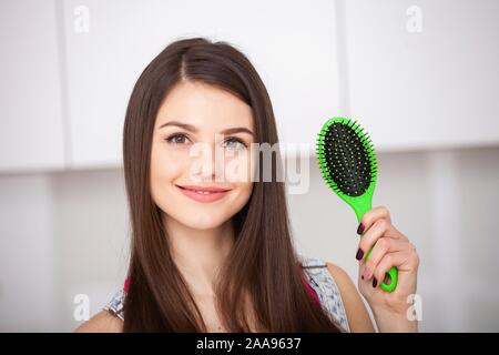 Girl est titulaire d'une brosse sans cheveux et souriant Banque D'Images