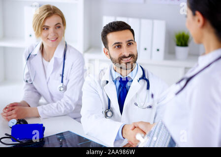 Jeune médecin arabe souriant serre la main d'une infirmière dans un hôpital. Groupe de jeunes médecins dans le bureau Banque D'Images