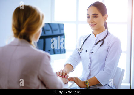 Médecin et patient. Femme médecin arabe et patient aborder quelque chose alors qu'il était assis à la table . La médecine et les soins de concept. Banque D'Images