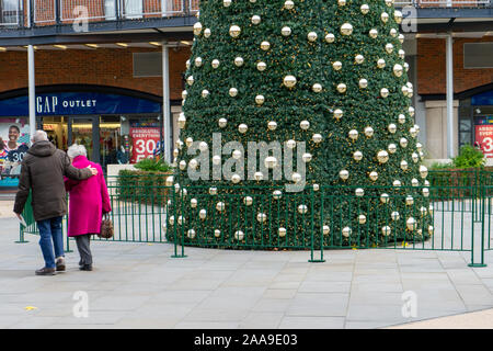 Les amateurs de Noël se prominent devant un grand arbre de noël au milieu d'un centre commercial à Portsmouth, Hampshire, Royaume-Uni Banque D'Images