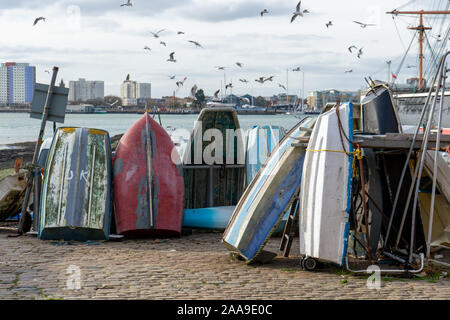 Vieux bateaux en bois empilés sur un quai ou un quai avec des mouettes survolant à Portsmouth, Hampshire, Royaume-Uni Banque D'Images