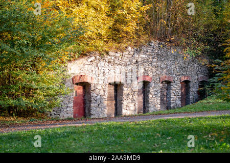 Vieux mur de pierre avec de vieilles portes en bois dans le parc public en automne. Endroit pour se cacher à l'extérieur. Cachette dans le parc. Maison de colline de stockage abandonnée. Banque D'Images