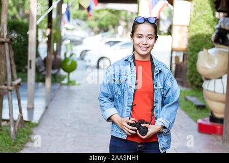 Voyageurs Asian girl portant une chemise, jeans et porter un appareil photo en attractions. Banque D'Images