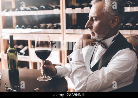 Sommelier Concept. Senior en remuant le verre de vin en vue du côté concerné close-up Banque D'Images
