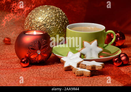Une tasse de café avec des biscuits à la cannelle en forme d'étoile, rouge et or boules de Noël et une bougie Banque D'Images