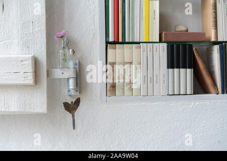 Détail d'une petite bibliothèque avec obturateur, joliment décoré avec un aster rose dans un petit vase en verre Banque D'Images