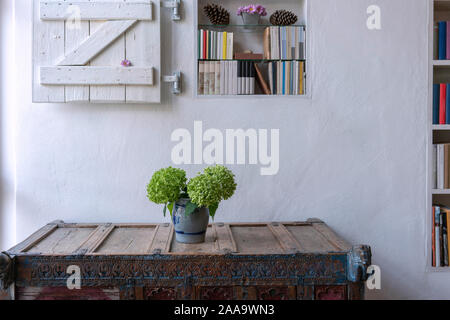 Close up de fleurs sur une armoire en face d'un mur blanc avec petite étagère décorée avec obturateur en bois blanc Banque D'Images