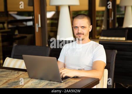 Homme avec portable à la caméra dans while sitting in cafe Banque D'Images