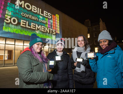 Deidrah Carrillo, Skye Zalenski, Evelina Venckute Sujlesh et Sharma, étudiants de troisième cycle à l'école de chimie à l'université d'Édimbourg posent avec leur téléphone mobile en face d'un affichage à l'Bristo Square, Édimbourg, montrant le tableau périodique en vie à venir à l'appui de la Semaine de la chimie. Banque D'Images