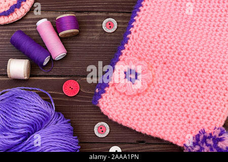 Bébé tricoté et pantoufles, des fils à tricoter sur table en bois. La vue du sommet. Accessoires de couture. Banque D'Images