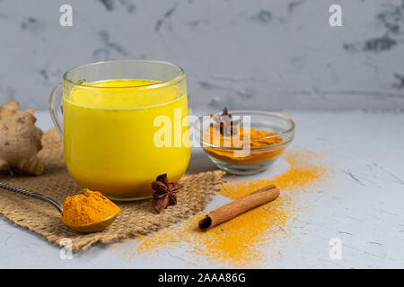 Lait d'or avec des épices. Le curcuma, girofle, poivre noir et une goutte d'huile végétale. Boisson traditionnelle indienne. Sur un fond clair. La saine alimentation C Banque D'Images