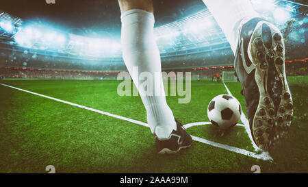 Scène de nuit football match avec gros plan d'une chaussure de soccer frapper la balle du coup de pied de coin Banque D'Images