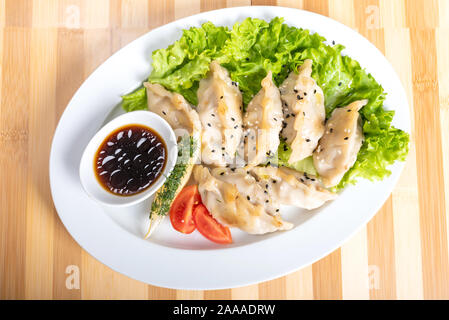 Gyoza sur une assiette, avec des herbes et de la sauce. Banque D'Images