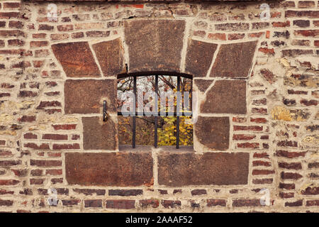 Détail de l'ouverture / échappatoire avec grille en fer rouillé encadrée de blocs de pierre dans une ancienne maçonnerie brique / mur de fortification de Vyšehrad, à Prague Banque D'Images