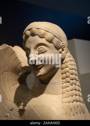 Gros plan sur la tête humaine sculpté avec de longs cheveux et un léger sourire sur le corps d'un sphinx. La sculpture est dans la Corinthe Grèce musée. Banque D'Images