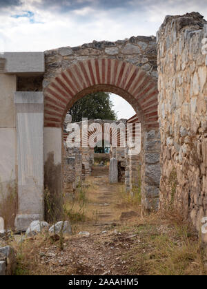 Série d'arcades en pierre qui sont renforcées avec de la brique et le mortier avec un mur en pierre en premier plan et ciel nuageux au-dessus. La voie de terre a des mauvaises herbes. Banque D'Images