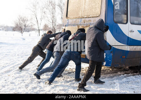 Une foule de personnes poussent un bus qui est bloqué dans la neige. Des conditions météorologiques sévères. La neige paralyse le trafic. Banque D'Images