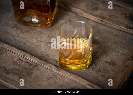 Close up of golden whisky chatoyantes dans un verre et la bouteille sur un vieux fût de chêne minable Banque D'Images