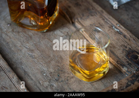 Brillant or whisky dans un verre et la bouteille sur un vieux fût de chêne minable Banque D'Images