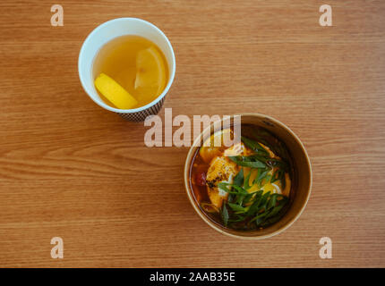 Soupe Asiatique dans une tasse de papier avec Thé au citron sur la table en bois Banque D'Images