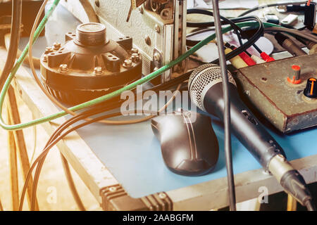 Un vieux microphone à condensateur noir et une souris noire placée sur une table de contrôle audio avec un câble emmêlé dans l'air extérieur utilisé pour les annonces. Banque D'Images