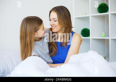 Famille heureuse de jouer à la maison. Mère et enfant filles se détendre et s'amuser au lit dans un matin de semaine Banque D'Images