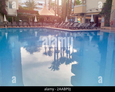 Piscine, transats et parasols pliés sous le soleil de matin d'été. Banque D'Images