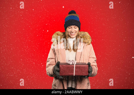 Heureusement une jeune femme est titulaire d'un cadeau de Noël dans sa main et il neige Banque D'Images