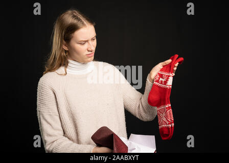Une jeune femme déçue contient jusqu'son cadeau chaussettes Banque D'Images