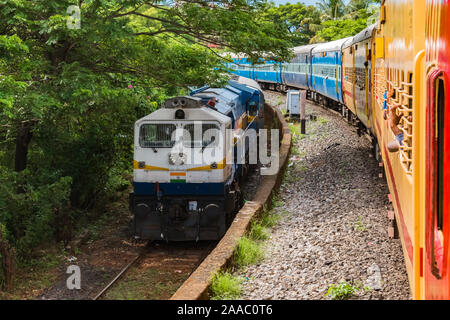 Deux Trains des chemins de fer indiens en parallèle dans des directions opposées se croisent les uns les autres à faible allure, au milieu des collines Western Ghats. -Droit Banque D'Images