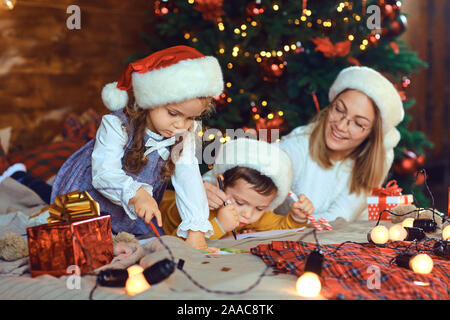 Maman avec enfants attire dans la pièce avec l'arbre de Noël. Banque D'Images